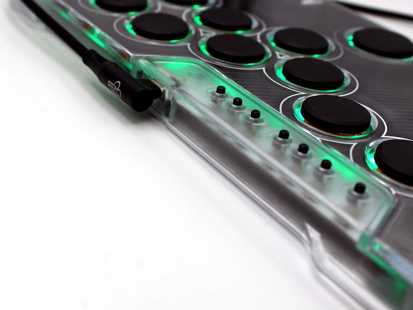 Close-up of the Snack Box MICRO leverless FGC fight stick controller showing the option buttons and attached USB-C cable